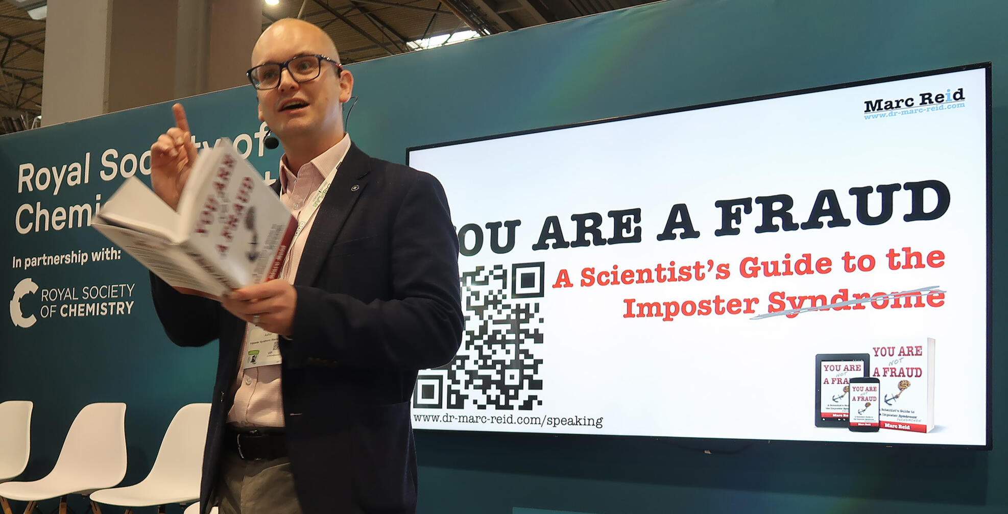 Untitled Marc Reid delivering a reading from the book You Are (Not) a Fraud) as part of an Imposter Syndrome keynote for a exhibition audience.